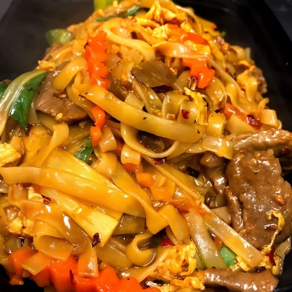 Close-up of Thai Village's Pad See Ew with wide noodles, beef, and colorful vegetables.